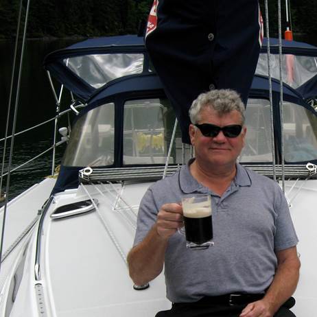 Greg sitting on his boat enjoying a beer t the end of a crusiing day.